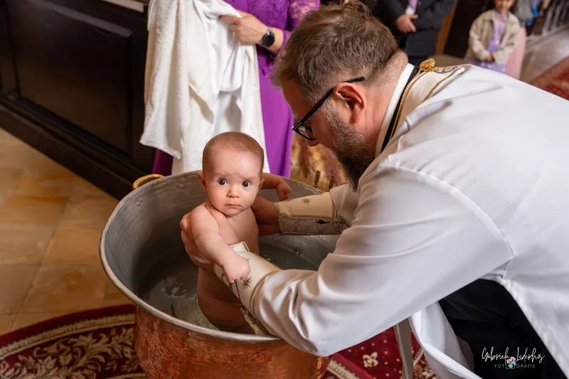 Priester tauft das Baby im Taufbecken