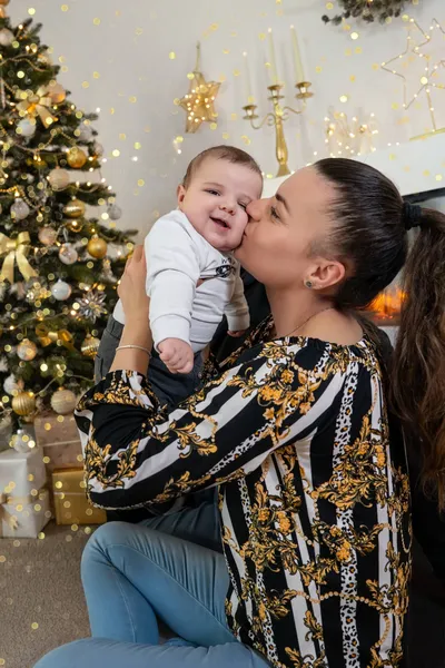 Mama küsst ihr lächelndes Baby auf die Wange