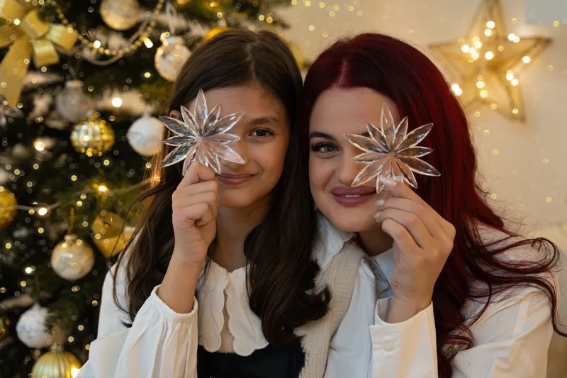 Zwei Frauen halten durchsichtige Weihnachtssterne vor jeweils ein Auge