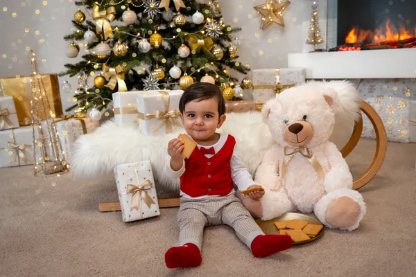Kleiner Junge mit roter Weste und Gebäck sitzt neben einem großen Teddy