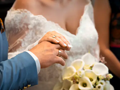 Hände des Brautpaars mit Ringen und Calla-Strauß
