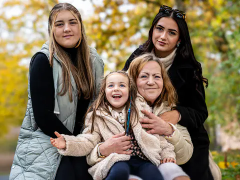 Drei Generationen lachen draußen im Herbstlaub