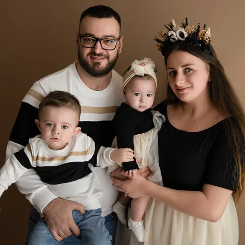 Eltern mit zwei Kleinkindern im Studio vor warmem Braun