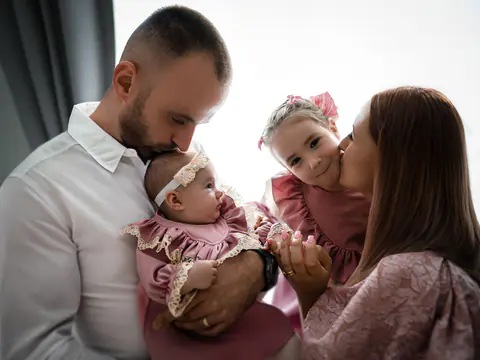 Eltern im hellen Studio, der Papa küsst das Baby, die Mama die Tochter
