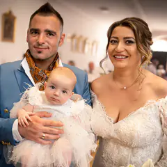 Brautpaar mit dem Baby im Tüllkleid lächelt in die Kamera