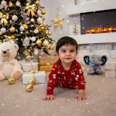Kleinkind krabbelt im Weihnachtsset mit Baum und Teddys