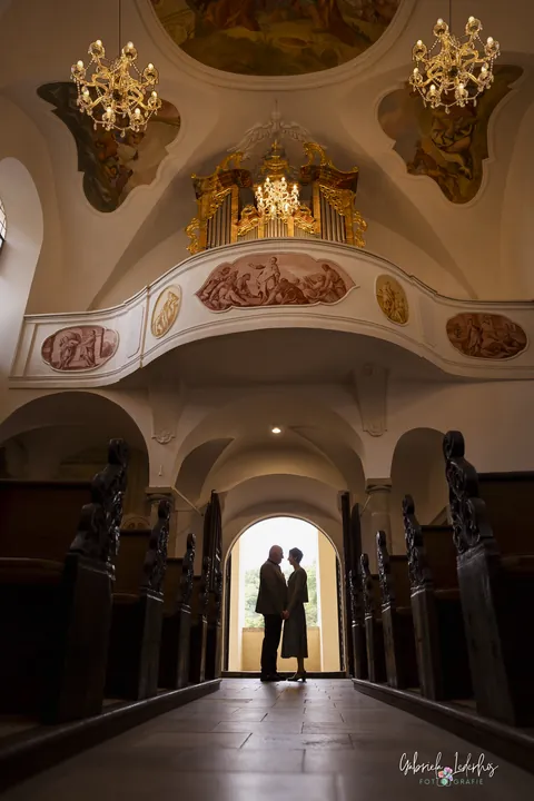Brautpaar als Silhouette in der Kirchentür, barocke Decke darüber